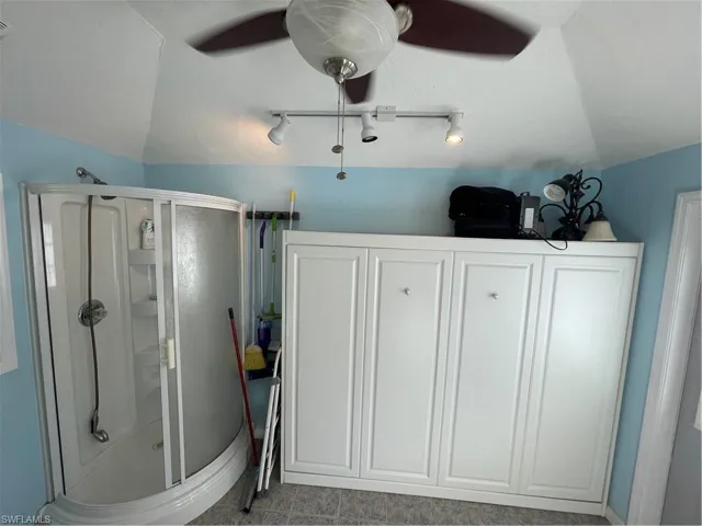 Bathroom with vaulted ceiling, a stall shower, and rail lighting