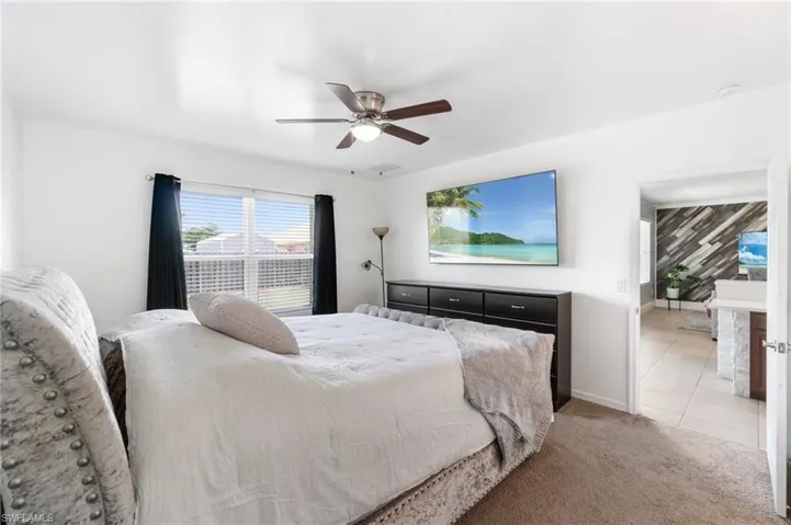 Primary bedroom featuring light colored carpet and ceiling fan