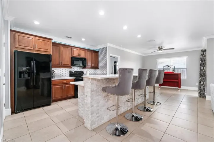 Kitchen featuring black appliances, custom cabinets, backsplash & large pantry.