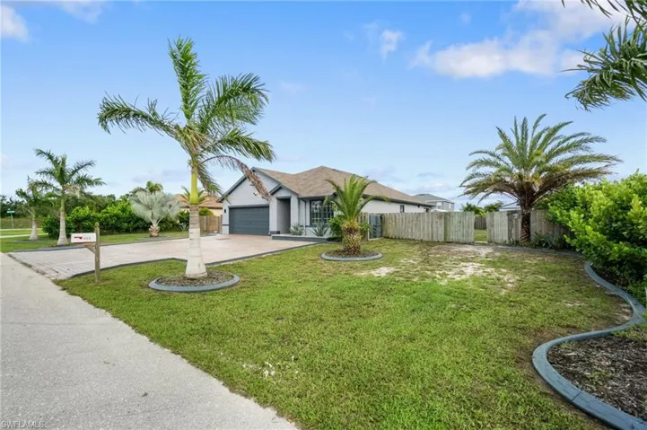 Single story home with a front yard full of custom landscaping and Florida palms