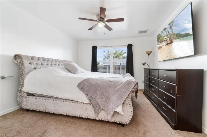 Primary bedroom with natural light, ceiling fan and light colored carpet