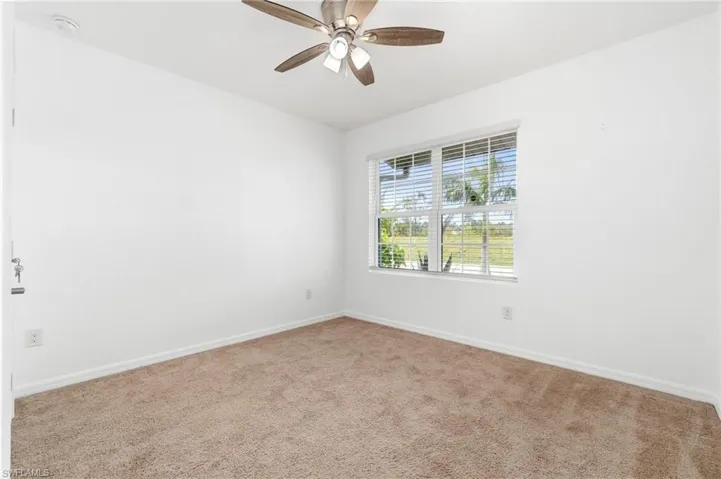 Secondary bedroom with neutral carpet & ceiling fan.