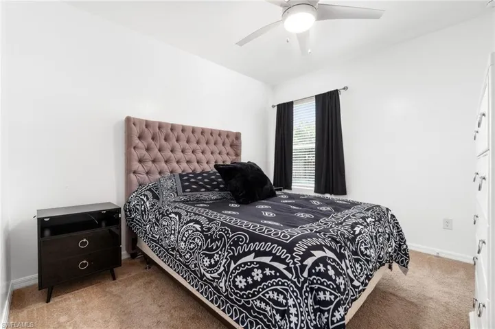 Secondary bedroom with ceiling fan and neutral carpet flooring.