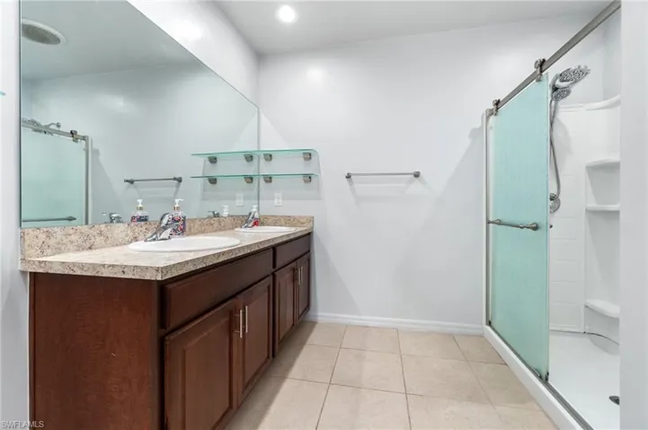 Bathroom with tile flooring, an enclosed shower, oversized vanity, and double sink