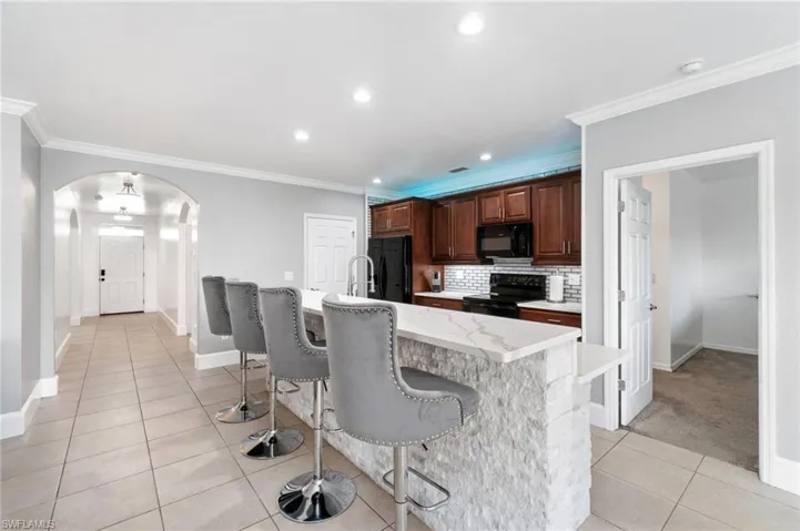 Kitchen with custom backsplash, and extended center island with sink, black appliances