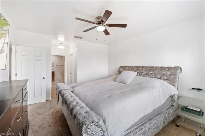 Primary bedroom overlooking backyard, featuring light colored carpet