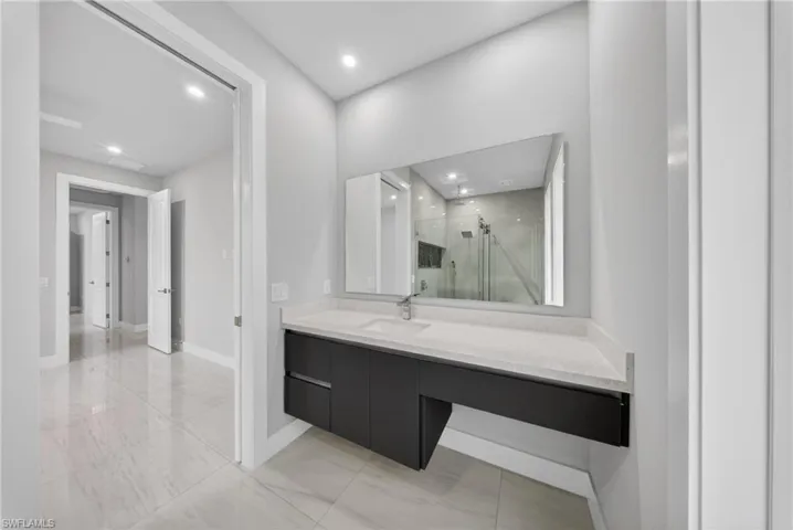 Modern vanity area featuring a floating black cabinet, light-toned countertop, and an integrated rectangular sink