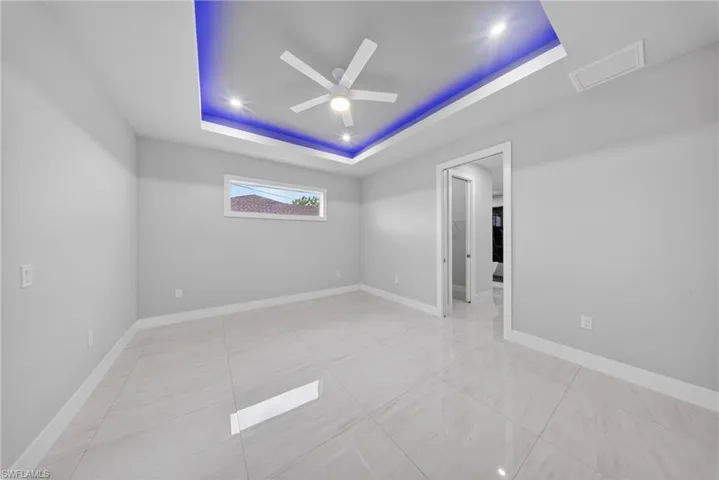 Tray ceiling with accent lighting, recessed lighting, and a ceiling fan