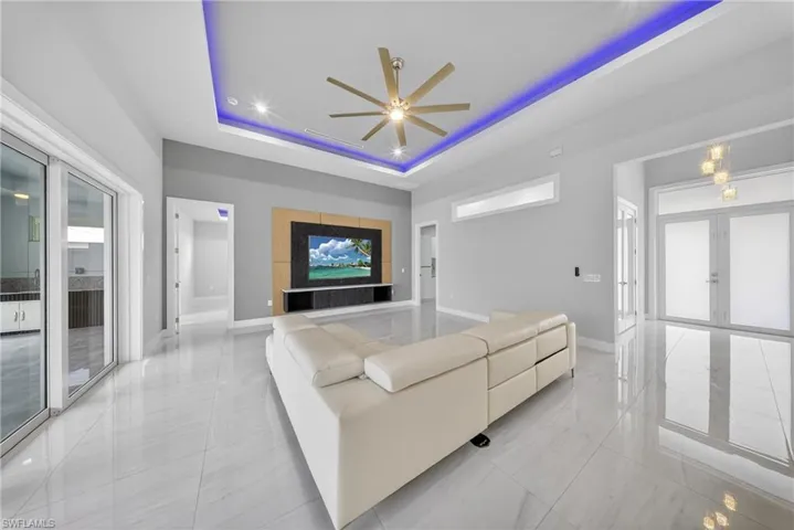 Open concept living area featuring large format tile flooring and a tray ceiling with integrated lighting