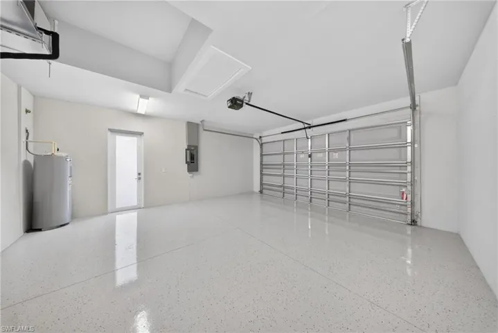 Spacious garage featuring a durable epoxy-coated floor, a translucent entry door, and an automatic garage door opener