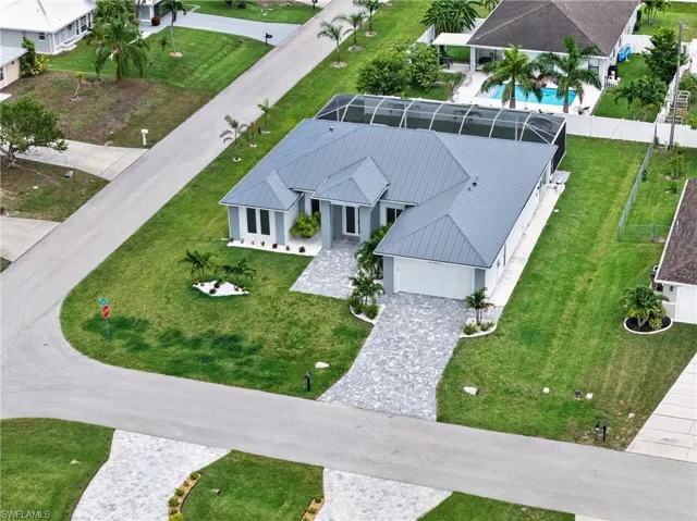 Contemporary residence featuring a gray metal roof, screened lanai, and an attached two-car garage