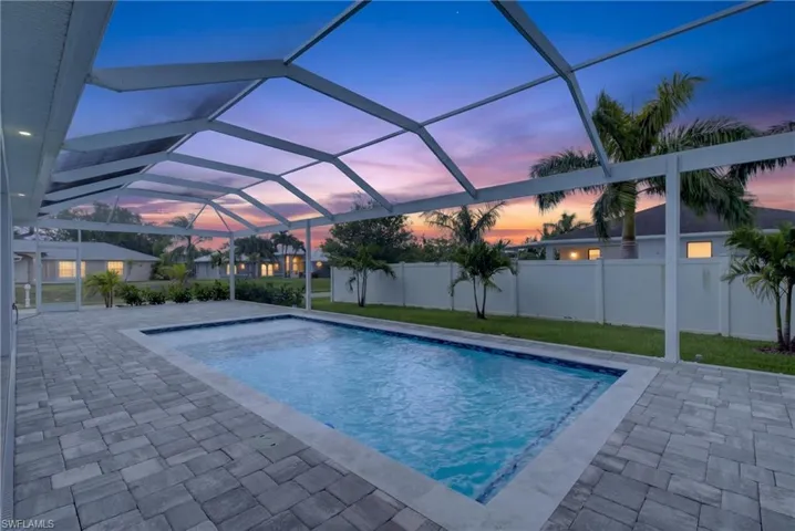 Screened outdoor living area featuring a rectangular swimming pool with blue tile accents