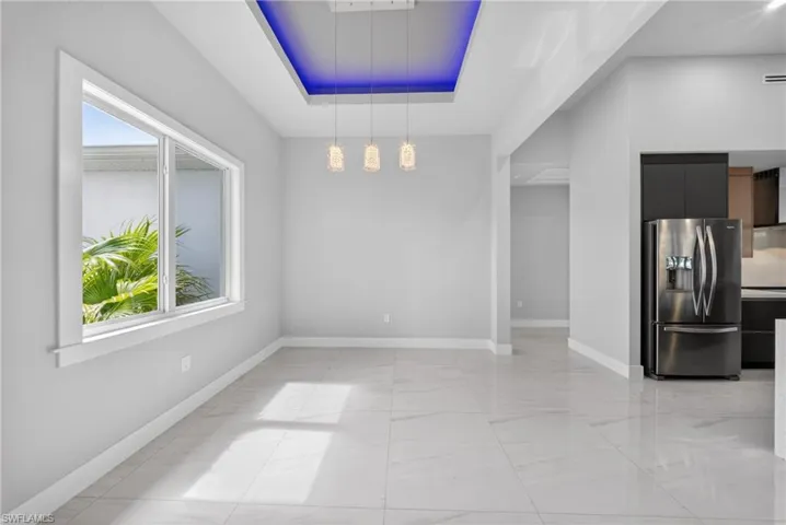 Open-concept dining area featuring light gray walls and large format tile flooring