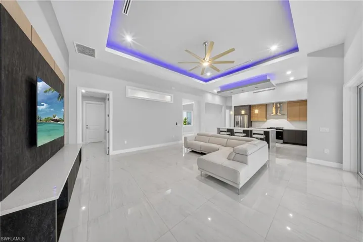 Open-concept living space featuring high ceilings with tray detailing and ambient lighting