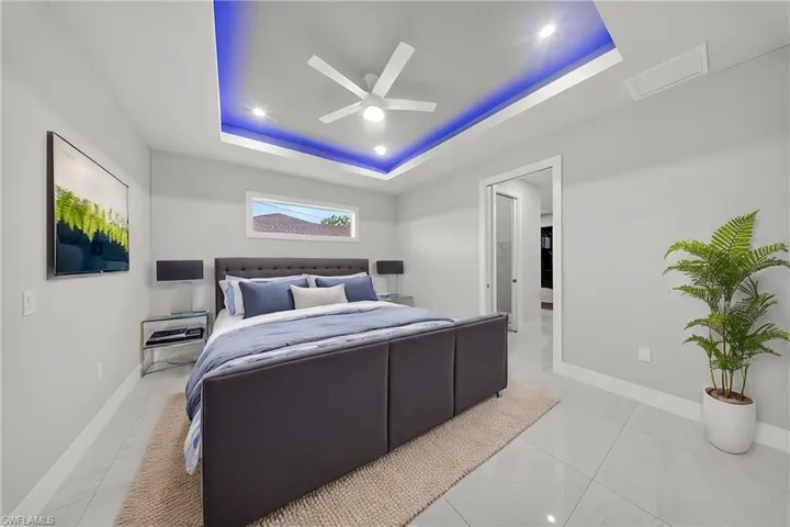 Recessed lighting and a ceiling fan illuminate the room, showcasing the tray ceiling with accent lighting
