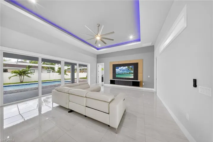 Spacious living area featuring polished tile flooring and a recessed ceiling with integrated accent lighting