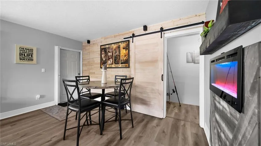 Dining space featuring wooden walls, a barn door, wood finished floors, an accent wall, and a textured ceiling