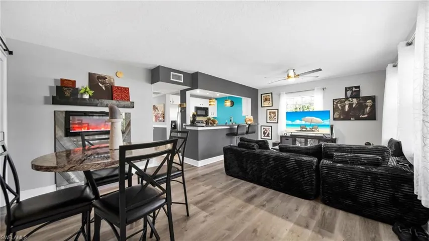 Living room featuring a glass covered fireplace, wood finished floors, and a ceiling fan