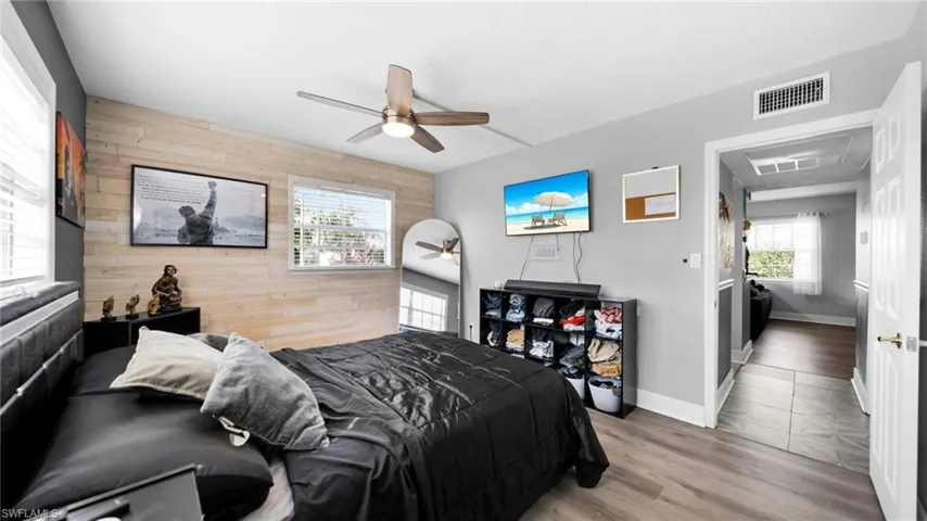 Bedroom featuring wooden walls, wood finished floors, and ceiling fan