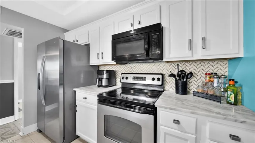 Kitchen featuring stainless steel appliances, white cabinets, and tasteful backsplash