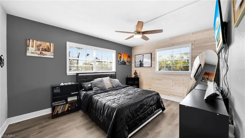 Bedroom featuring wood walls, wood finished floors, and a ceiling fan