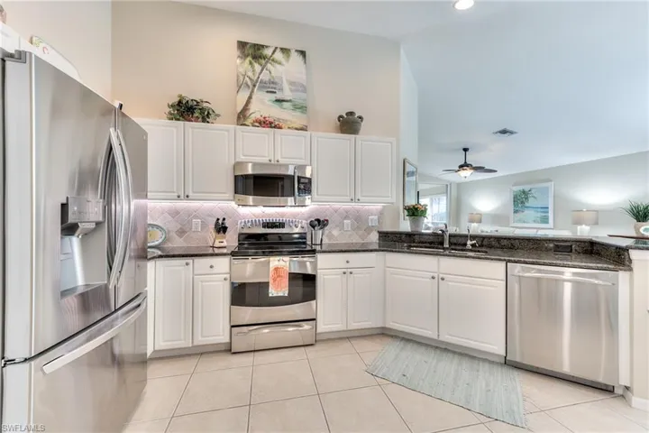Kitchen featuring sink, white cabinets, dark stone counters, and stainless steel appliances