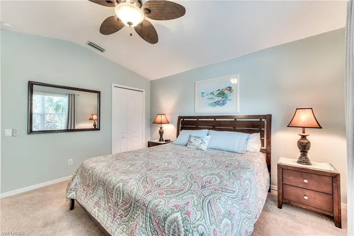 Carpeted bedroom featuring a closet, vaulted ceiling, and ceiling fan