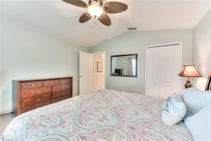 Carpeted bedroom with a closet, ceiling fan, and vaulted ceiling