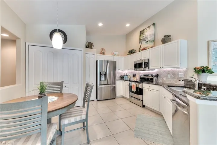 Kitchen with white cabinetry, light tile patterned floors, decorative backsplash, sink, and stainless steel appliances