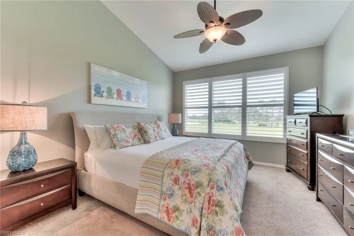 Carpeted bedroom featuring ceiling fan and lofted ceiling