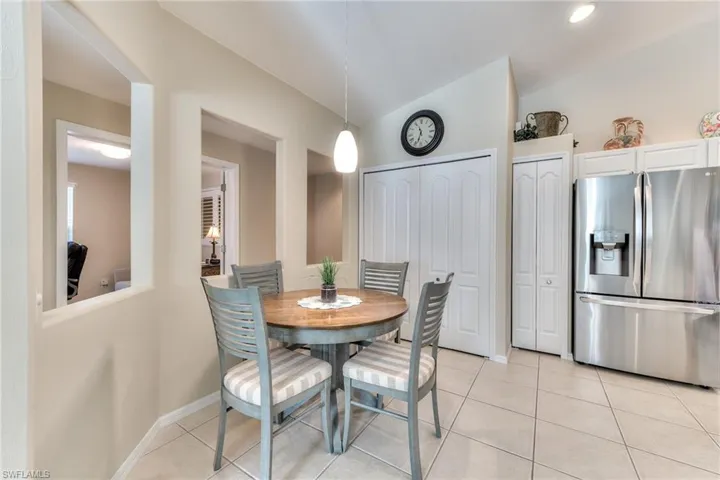Tiled dining room featuring vaulted ceiling