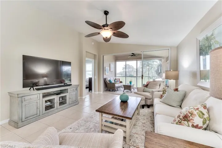 Living room featuring ceiling fan, light tile patterned floors, and lofted ceiling