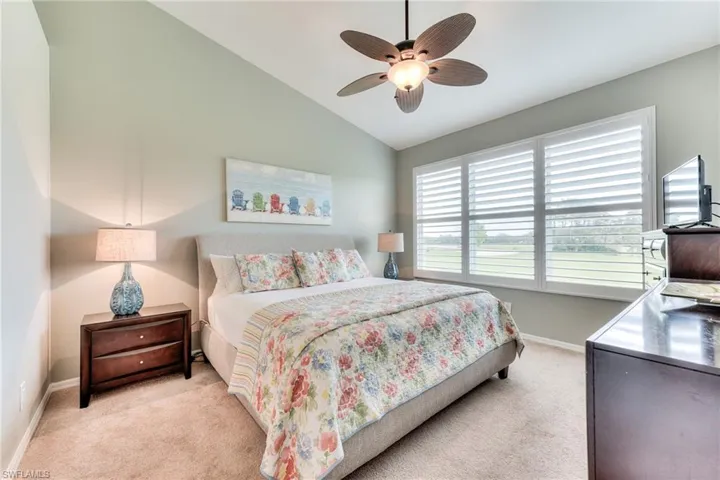 Carpeted bedroom featuring ceiling fan and lofted ceiling