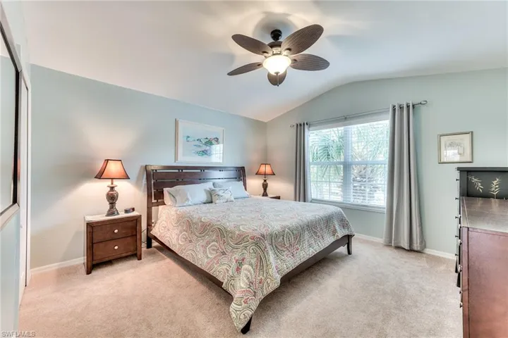 Bedroom with a closet, ceiling fan, light colored carpet, and vaulted ceiling