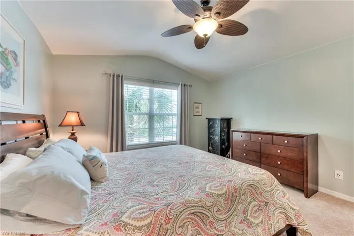 Bedroom with ceiling fan, light colored carpet, and lofted ceiling