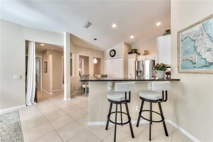 Kitchen with stainless steel fridge with ice dispenser, hanging light fixtures, kitchen peninsula, a breakfast bar area, and light tile patterned flooring