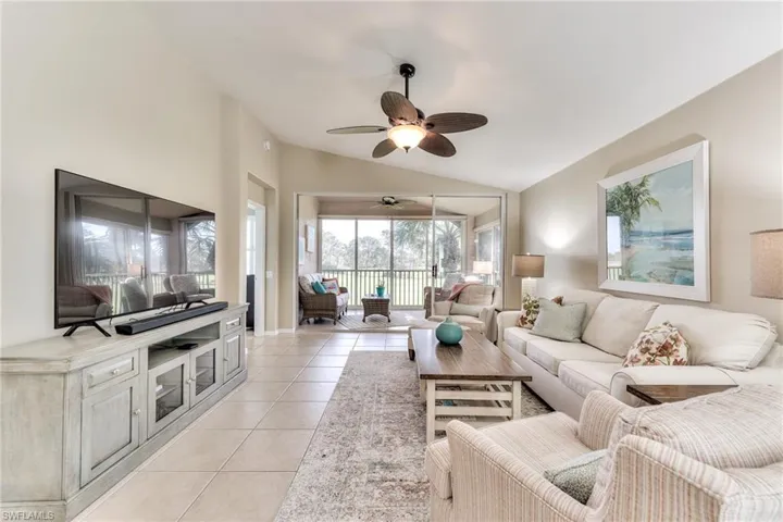 Living room with ceiling fan, light tile patterned floors, and lofted ceiling