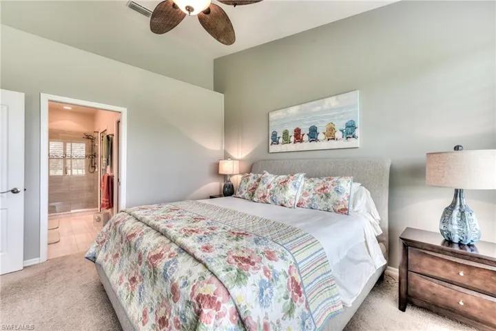 Bedroom with ceiling fan, connected bathroom, and light carpet