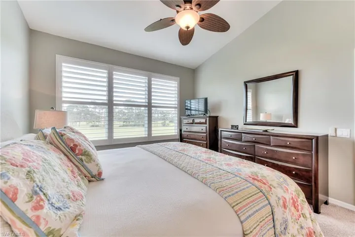 Carpeted bedroom with vaulted ceiling and ceiling fan