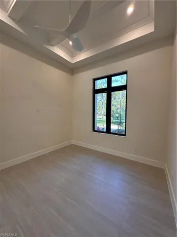 Empty room with recessed lighting, a ceiling fan, a tray ceiling, and crown molding
