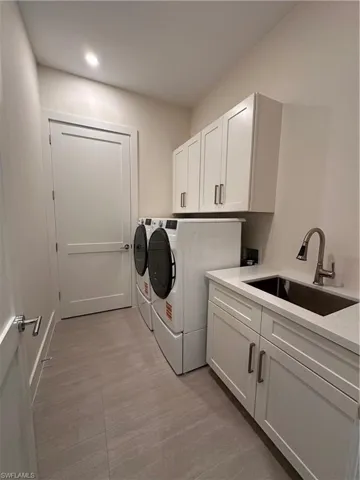 Washroom featuring cabinet space, washer and clothes dryer, and light wood-type flooring