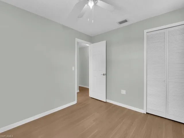 Unfurnished bedroom featuring wood finished floors, baseboards, a closet, and ceiling fan