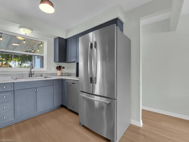Kitchen with appliances with stainless steel finishes, a sink, light wood finished floors, and light countertops