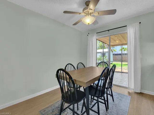 Dining area with baseboards, a ceiling fan, a textured ceiling, and light wood-type flooring