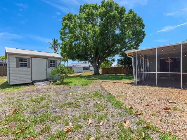 View of yard featuring a sunroom, fence, a storage shed, and an outdoor structure