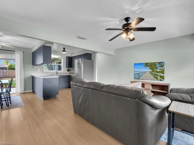 Living area featuring ceiling fan, light wood finished floors, and a textured ceiling