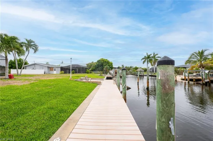 View of dock featuring a lawn and a water view