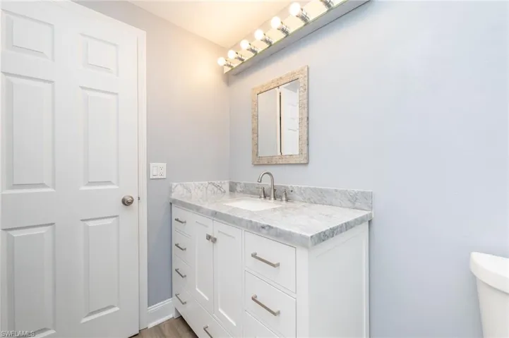 Bathroom with hardwood / wood-style floors, vanity, and toilet