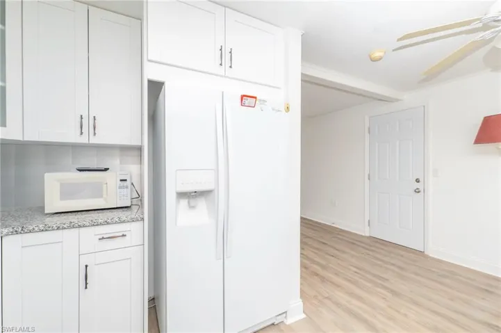 Kitchen with white cabinets, ceiling fan, white appliances, and light wood-type flooring