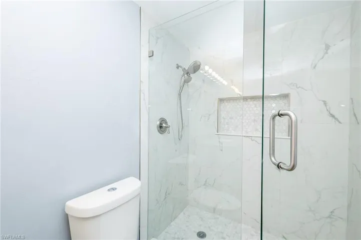 Bathroom featuring a shower with shower door and toilet